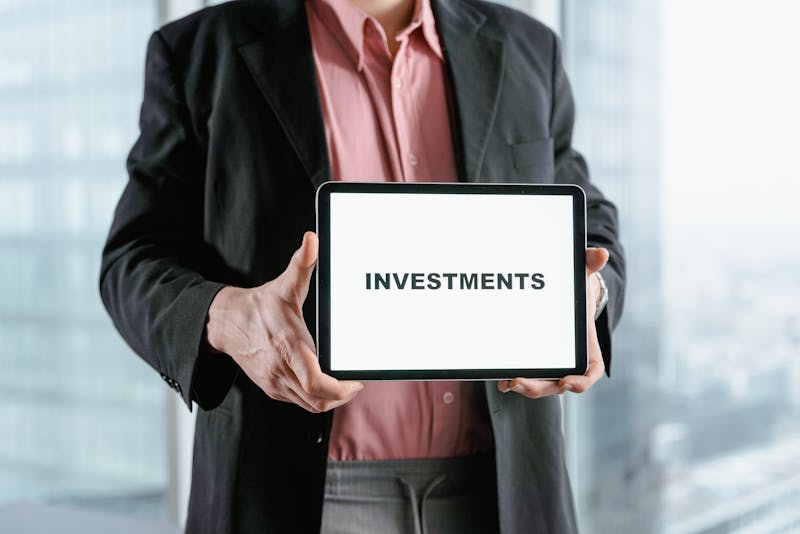 a man on a suit holding a table with the word investments written on it